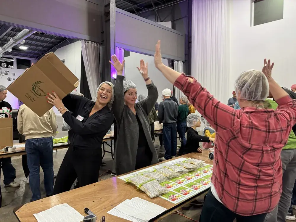 Community group volunteers celebrating at a Harvest Pack event