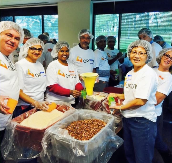 A corporate volunteer team in hairnets at a packing event